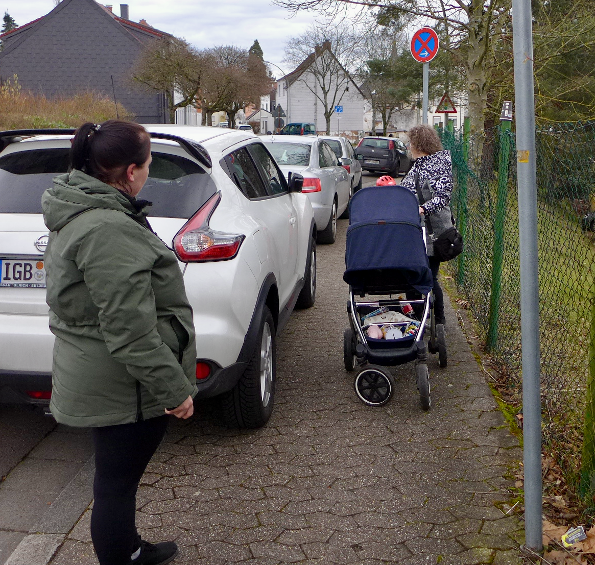 Ein parkendes Auto macht den Gehweg sehr eng. Kinderwagen und Fußgängerin kommen nicht aneinander vorbei.er